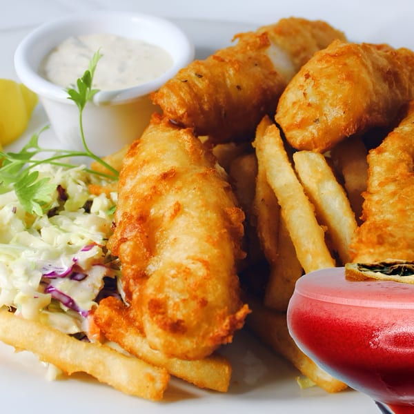 Rosie McCann's Irish Pub's fish and chips with coleslaw, tartar sauce, lemon, and a red cocktail.