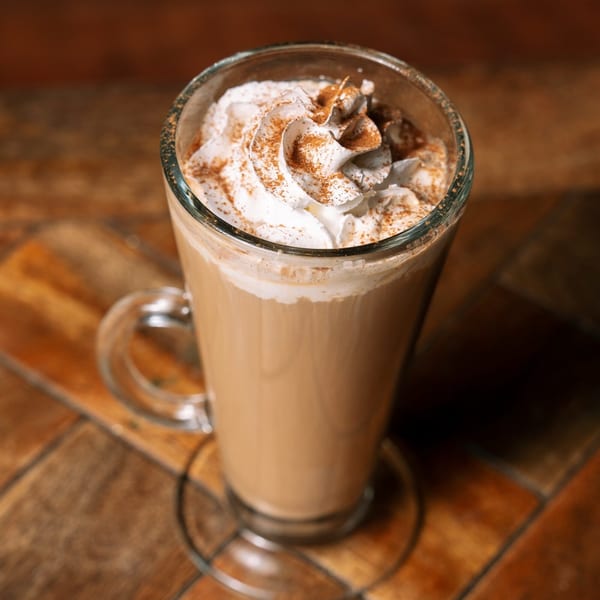 Irish coffee in a clear mug, topped with whipped cream and a sprinkle of cinnamon.
